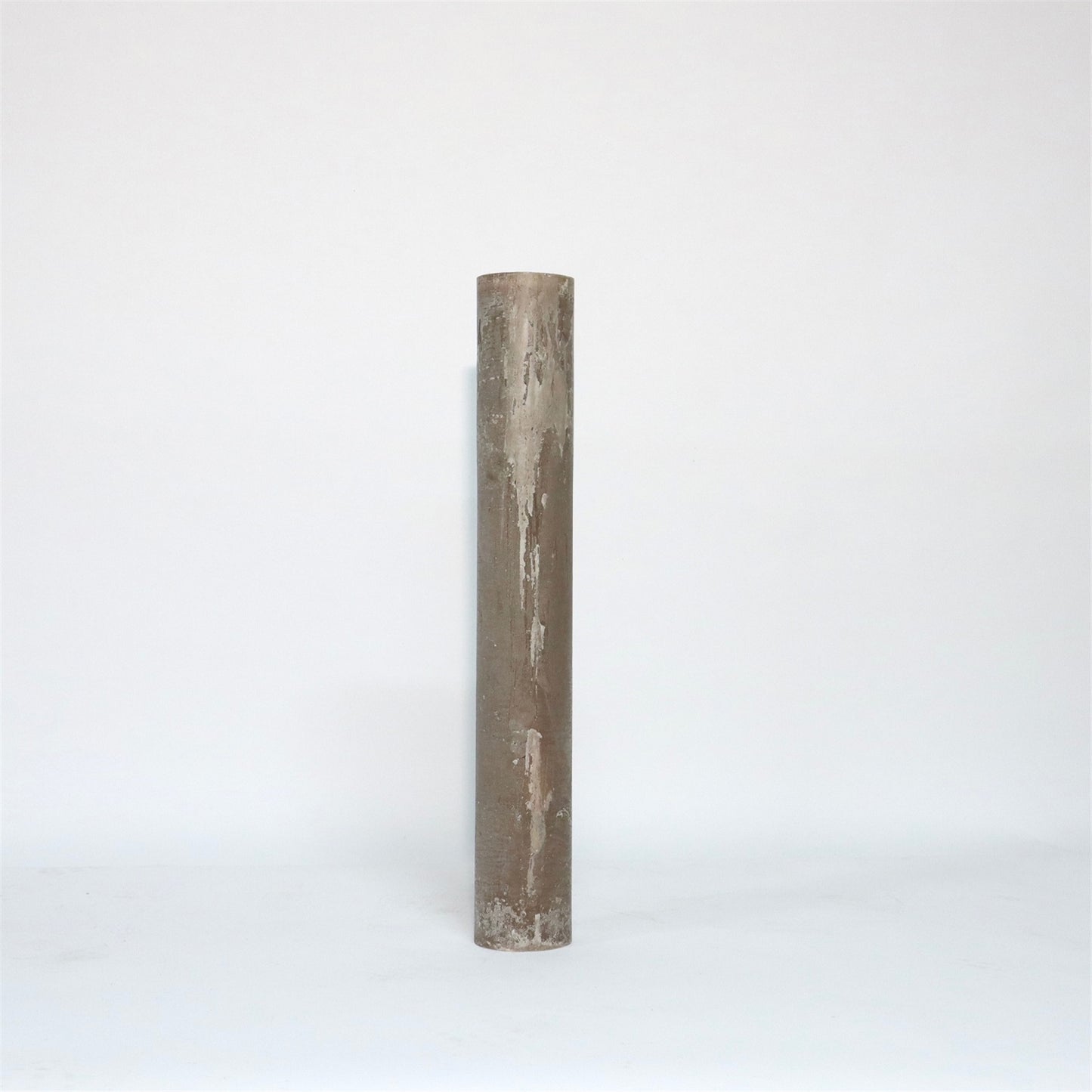 A tall, cylindrical, beige candle with a textured surface standing upright against a plain white background.