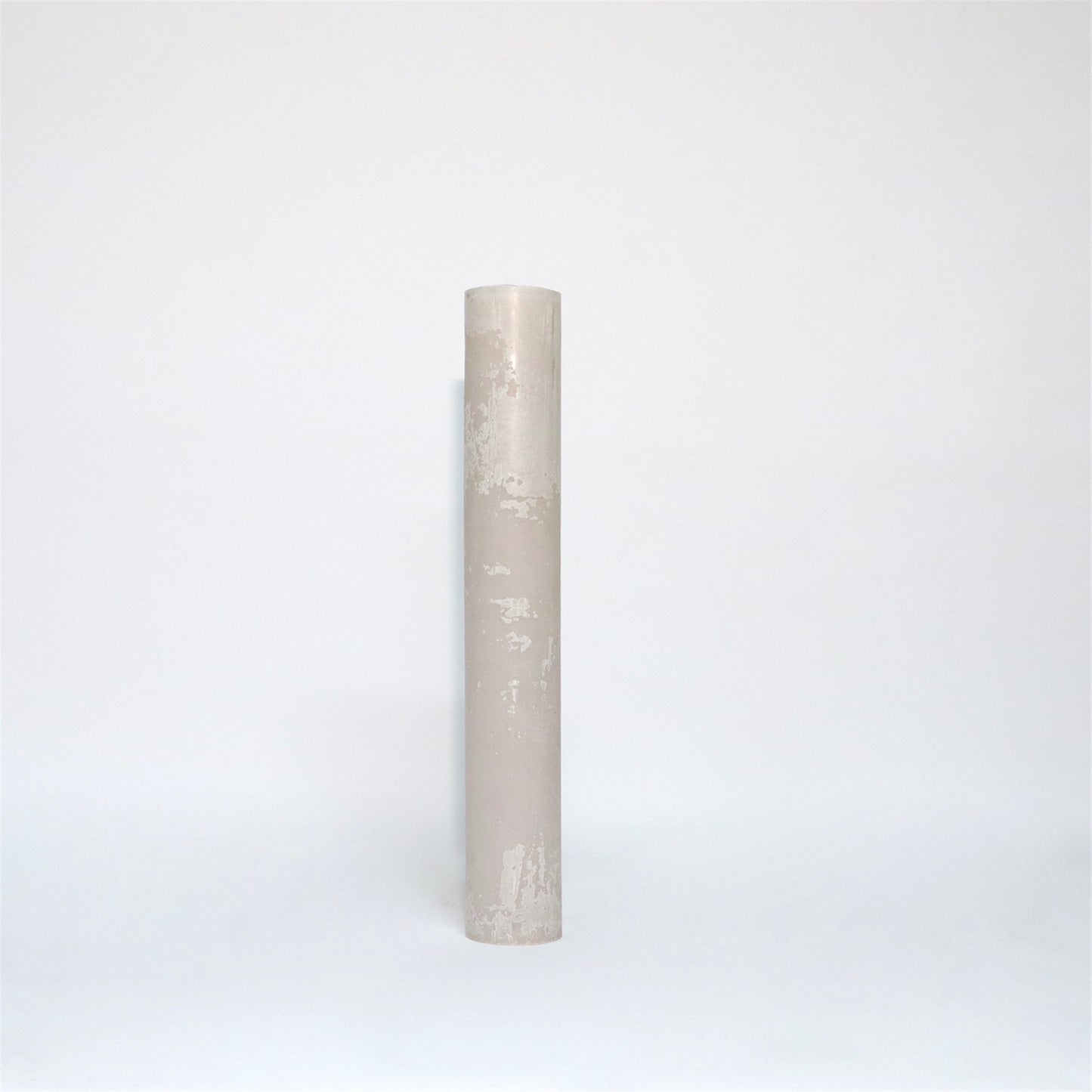 A tall, cylindrical, white candle with a textured surface standing upright against a plain white background.