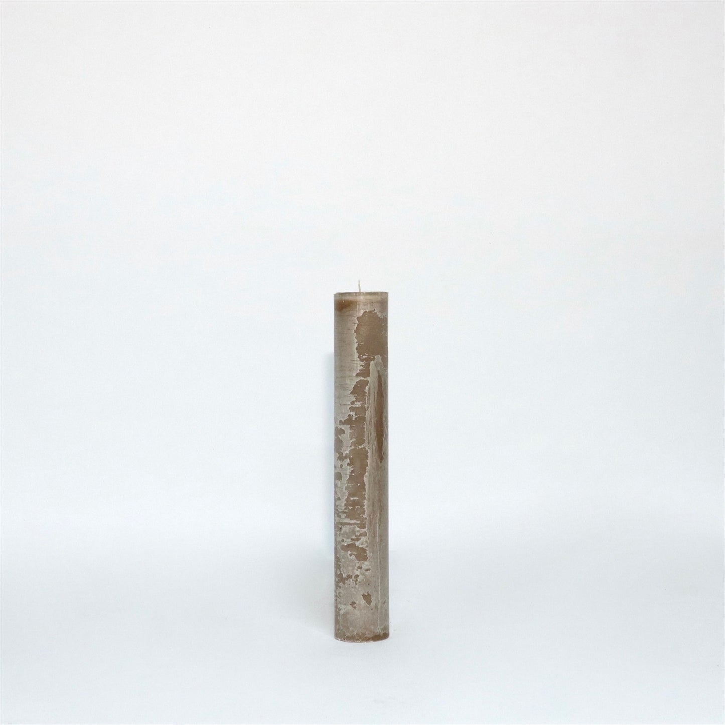 A tall, cylindrical, beige candle with a textured surface standing upright against a plain white background.